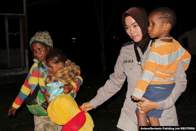 Seorang petugas polisi mengevakuasi warga Papua setelah bentrokan antara aparat keamanan dan pemberontak separatis, di Mimika, Papua, 8 Maret 2020. (Foto: Antara/Sevianto Pakiding via REUTERS)