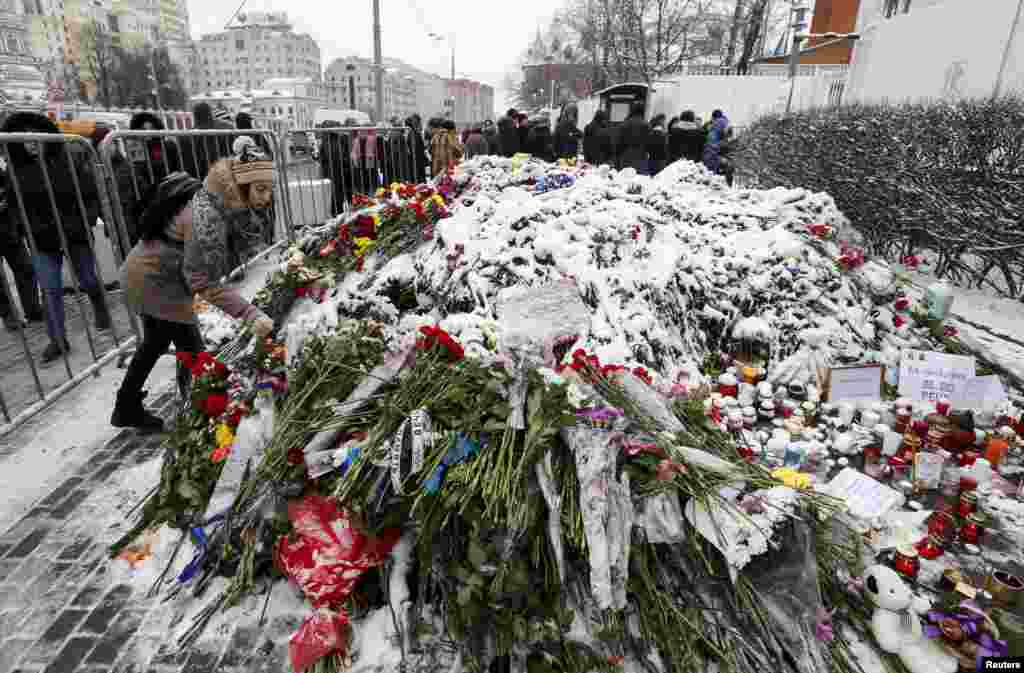 Seorang perempuan meletakkan bunga di dekat kedutaan besar Perancis di Moskow, Rusia, untuk mengenang para korban serangan teror di Paris.