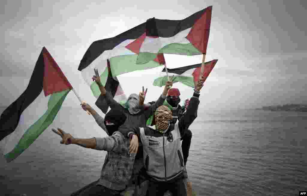 Palestinians wave national flags before a convoy of boats is launched at the initiative of the &quot;Intifada Youth Coalition&quot; (IYC) to break the naval blockade of Gaza as a protest against the Israeli siege of the port in Gaza city.