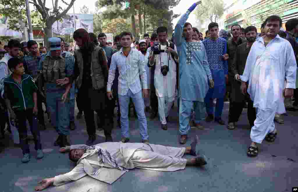 An Afghan official says government troops have regained control of the main square in Kunduz, a strategic northern city briefly seized by Taliban insurgents last week. In this photo, an Afghan protester lies on the ground to block one of the main streets during a demonstration against the government, Kabul, Afghanistan, Oct. 7, 2015.