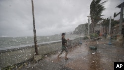 A man battles strong winds and rain from Typhoon Hagupit in Legazpi, Albay province, eastern Philippines, Dec. 7, 2014.