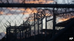FILE - Dawn breaks at the now closed Camp X-Ray, used as the first detention facility for suspected militants captured after the Sept. 11 attacks, at the Guantanamo Bay Naval Base in Cuba.
