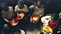 A group of young Rwandans eat at the orphanage run by American Rosamund Carr near Gisenyi, Rwanda, (File July 20, 1997). 