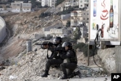 FILE - Israeli border policemen aim their weapons during clashes with Palestinian students in Abu Dis, West Bank.