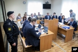 FILE- Alexei Navalny, foreground, second left, and Alisher Usmanov's lawyer Genrikh Padva, right, attend hearings in court in Moscow, Russia, May 30, 2017.