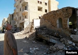 FILE - A man looks at damage at a site hit by what activists said was an airstrike by forces loyal to Syria's President Bashar al-Assad in Raqqa, an Islamic State power base in Syria, Sept. 8, 2014.