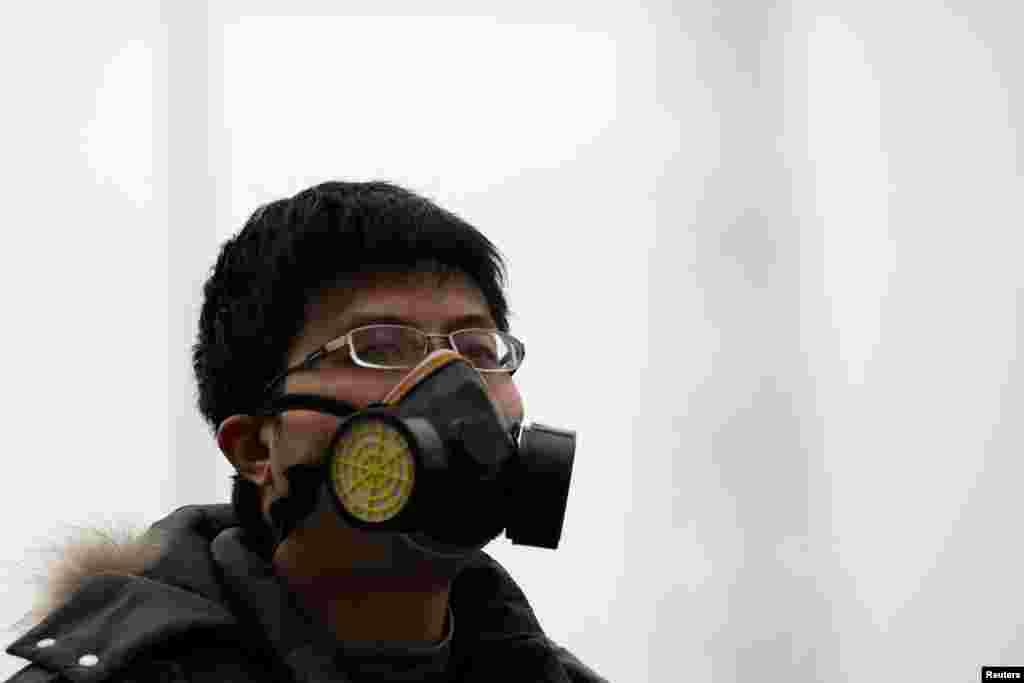 A man wearing a mask amid the heavy haze in Beijing, China. Beijing, under fire to take effective measures against air pollution, raised its four-tiered alert system to &quot;orange&quot; for the first time, as heavy smog was forecast to roll into the city over the next three days.