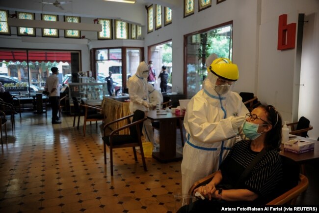 Para petugas kesehatan mengambil sampel untuk tes cepat antigen dari para pengunjung di tengah pandemi virus coronca (COVID-19) di Bandung, Jawa Barat, Rabu, 30 Desember 2020. (Foto: Antara Foto/ Raisan Al Farisi via Reuters)