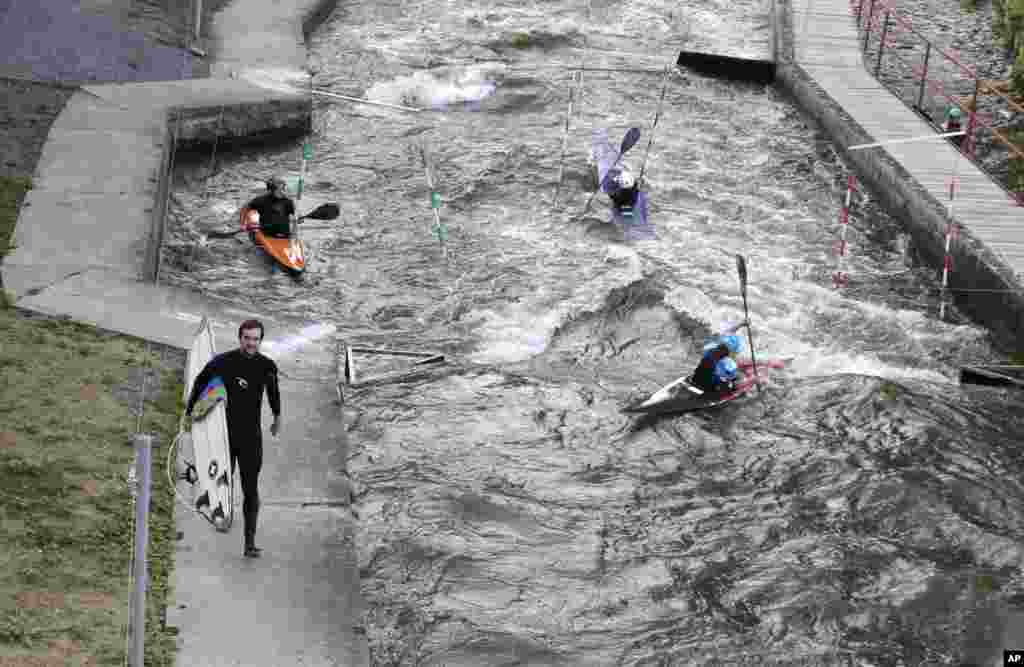 Martin Mrazek carries his surfboard along the Elbe river&#39;s channel with artificial waves in Brandys nad Labem, Czech Republic.