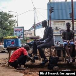 Ricci Shryock: An accountant gets his shoes shined on his way to work in Conakry, Guinea.