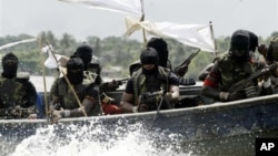 FILE - Militants with Kalashnikov assault rifles and rocket-propelled grenade launchers patrol creeks of the Niger Delta, southern Nigeria, Feb. 24, 2006.