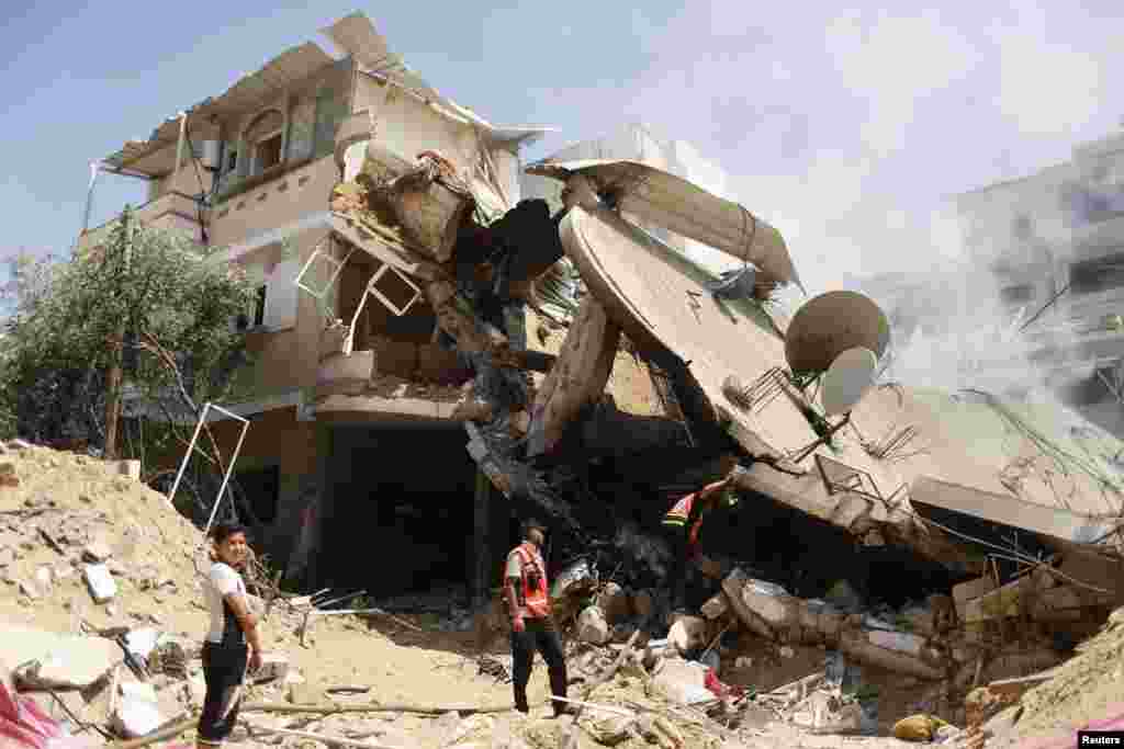 Palestinian rescue workers inspect the remains of a house that witnesses said was destroyed by an Israeli air strike, in Gaza City July 23, 2014.