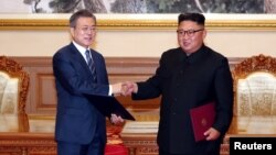 El presidente de Corea del Sur, Moon Jae-in (izquierda) estrecha la mano del líder norcoreano Kim Jong Un tras la firma de acuerdos en Pyongyang, Corea del Norte, el miércoles, 19 de septiembre de 2018.