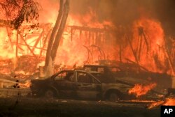 A wildfire burns a structure near Malibu Lake in Malibu, Calif., Nov. 9, 2018.