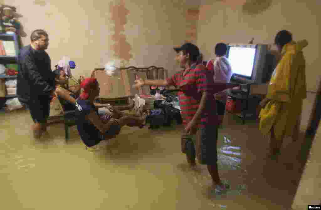 People try to watch television inside their flooded home in Mexico&#39;s resort city Cancun, June 4, 2013. 