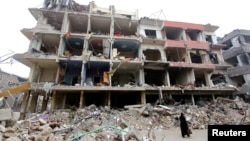 A woman walks past a damaged building in the Douma neighborhood of Damascus, Syria, Feb. 12, 2015.