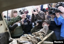 Journalists take photos and video of the body of a man, a Ukrainian serviceman according to separatist self-proclaimed Donetsk People's Republic (DNR) officials, in Donetsk, April 13, 2015.