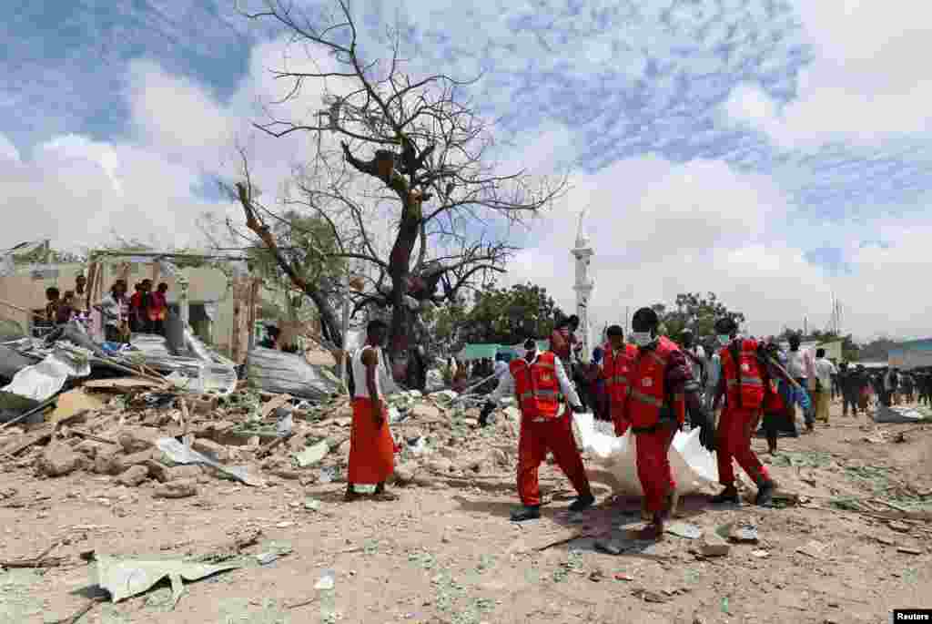 Rescuers carry the dead body of an unidentified man from the scene of an explosion to an ambulance in Hodan district, Mogadishu, Somalia.