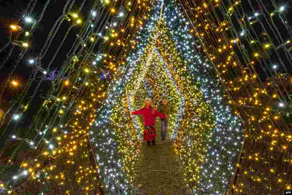 Children walk past 200,000 lights that decorate a winter wonderland at Naumkeag, part of the land managed by the Trustees of Reservations, in Stockbridge, Massachusetts, Dec. 13, 2020.