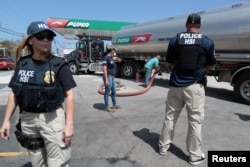 Federal agents provide security to a truck discharging gas at a gas station, after the island was hit by Hurricane Maria, in San Juan, Puerto Rico, Sept. 28, 2017.