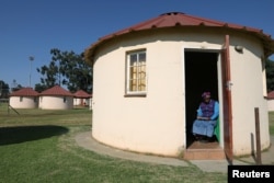 Zodidi Desewula, a housewife from the Eastern Cape province, takes a break by reading as seen through the doorway of her one-roomed rondavel house in Carletonville, South Africa, May 23, 2020. (REUTERS/Siphiwe Sibeko)