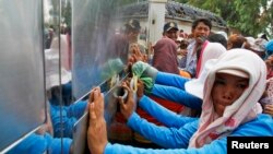 Garment workers push against the gates of a factory owned by Sabrina Garment Manufacturing during their protest in Kampong Speu province, west of the capital Phnom Penh, Cambodia, June 3, 2013.