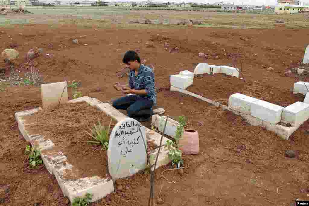 A man prays at the grave of a Free Syrian Army fighter at a cemetery at al-Karak al-Sharqi in Deraa, Syria, March 30, 2013. 