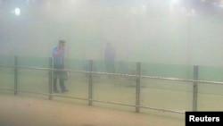 FILE - A policeman stands amid smoke at the arrival gate B after an explosion at Terminal 3 of Beijing Capital International Airport in Beijing, July 20, 2013.