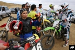 FILE - Iranian motocross rider Behnaz Shafiei, left, prepares for a training session at a racetrack near the village of Baraghan, west of the capital Tehran, June 5, 2015.