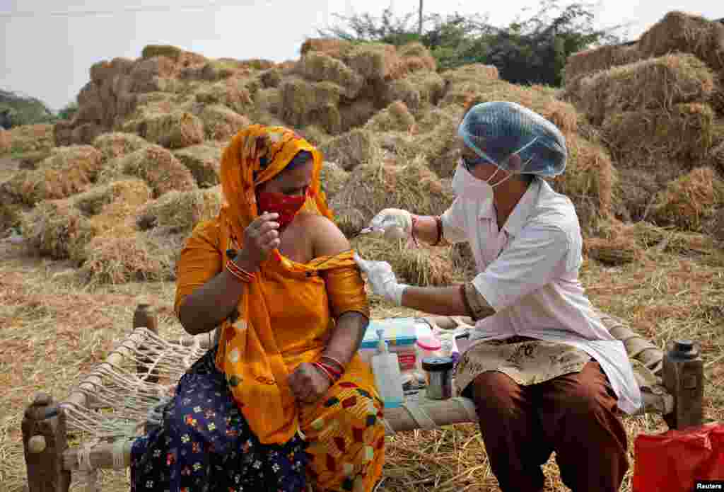 Jabuben Bharwad, 30, receives a dose of Covishield vaccine against COVID-19, that&#39;s manufactured by Serum Institute of India, while working in a field during a door-to-door vaccination drive at Mahijada village on the outskirts of Ahmedabad, India.