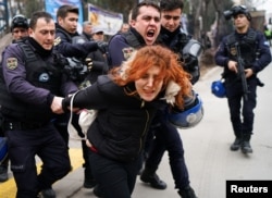 FILE - Riot police detain a demonstrator during a protest against the dismissal of academics from universities following a post-coup emergency decree, outside the Cebeci campus in Ankara, Turkey, Feb. 10, 2017.