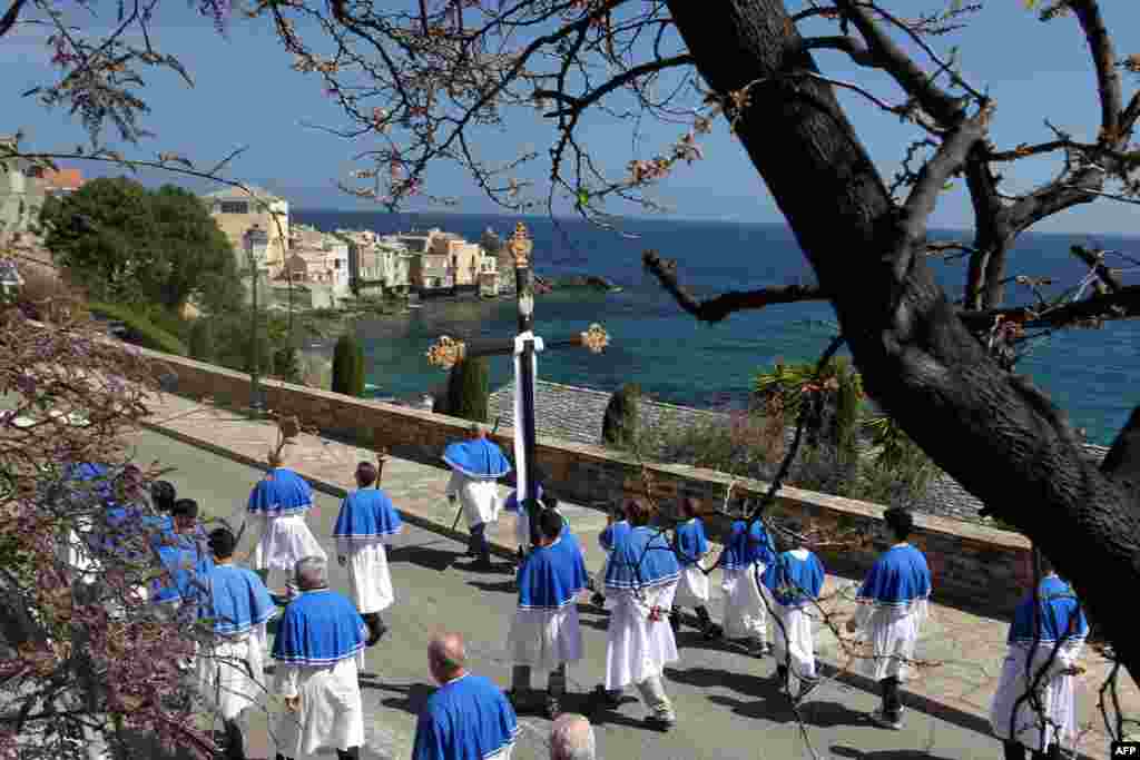 People carry a cross as they walk in procession on Good Friday, in the Brando area of the French Mediterranean island of Corsica, April 3, 2015.