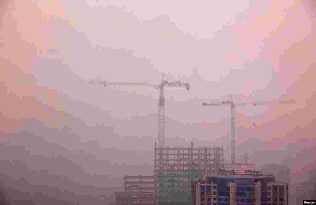 Cranes atop a residential building under construction in central Beijing, April 18, 2012. 