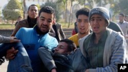 Egyptian men try to help save the life of an al-Azhar University student heavily injured from clashes outside the university in Cairo, Egypt, Sunday, Dec. 29, 2013.