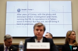 FILE - A tweet by President Donald Trump is displayed behind FBI Director Christopher Wray as he testifies during a House Judiciary hearing on Capitol Hill in Washington, Dec. 7, 2017, on oversight of the Federal Bureau of Investigation.