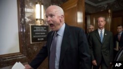 FILE - In this Oct. 25, 2017, file photo Senate Armed Services Chairman John McCain, R-Ariz., followed at right by House Armed Services Chairman Mac Thornberry, R-Texas, makes a humorous face to reporters on Capitol Hill in Washington. 