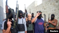 FILE - Masked Sunni gunmen pose during a patrol outside Fallujah, Iraq, April 28, 2014. 