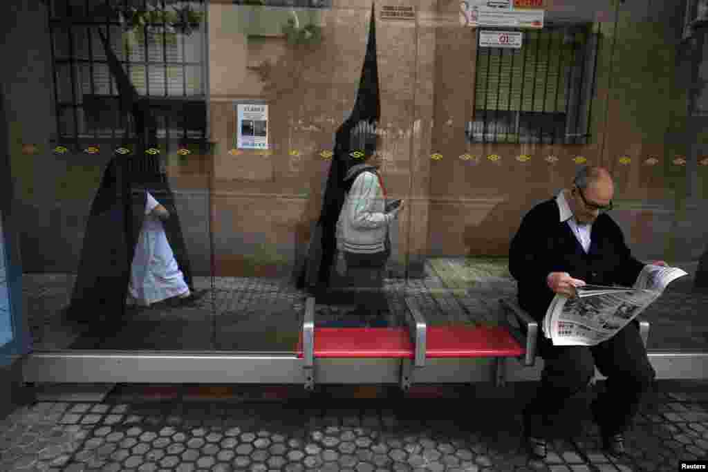 Dua orang berangkat ke gereja mereka sebelum mengambil bagian dalam prosesi &quot;Santa Genoveva&quot; selama Pekan Suci di kota Sevilla, Spanyol selatan. Ratusan prosesi Paskah berlangsung di Sevilla selama Pekan Suci, menarik ribuan pengunjung.