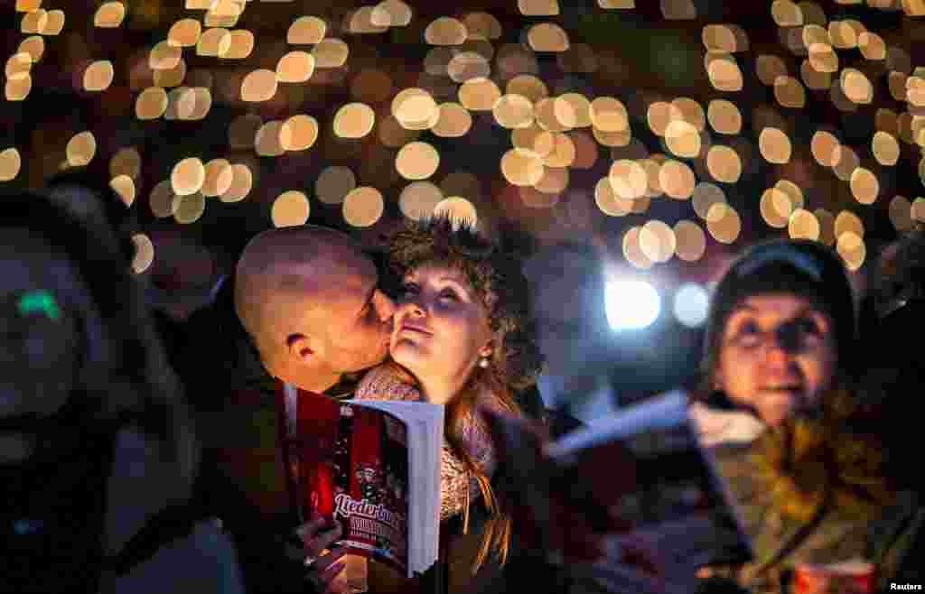 People attend the &#39;Weihnachtssingen&#39; a candle-light carol concert with 27,500 fans of the second-division club FC Union Berlin at the Alte Foersterei stadium in Berlin, Germany, Dec. 23, 2014.