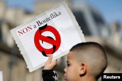 A young boy holds up a placard during a protest against President Abdelaziz Bouteflika seeking a fifth term in a presidential election set for April 18, in Paris, France, Feb. 24, 2019. Almost 70 percent of Algerians are under 30 years old .