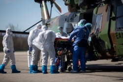 Medical staffs load a patient infected with the Covid-19 virus into a French military helicopter heading to Switzerland to ease the situation in eastern France, Monday, March 30 2020 in Strasbourg, eastern France.