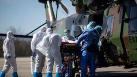 Medical staffs load a patient infected with the Covid-19 virus into a French military helicopter heading to Switzerland to ease the situation in eastern France, Monday, March 30 2020 in Strasbourg, eastern France.