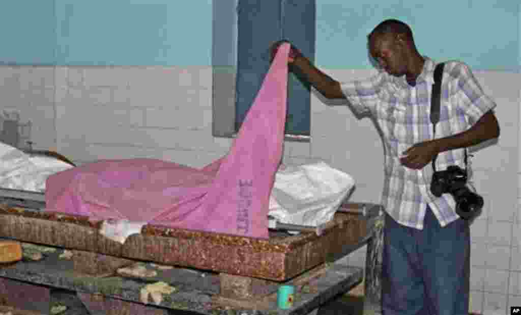 A Somali journalist inspects the body of fellow journalist Abdisalan Sheik Hassan, who was shot dead, at Madina hospital in Mogadishu, Somalia Sunday, Dec, 18, 2011. The director of Somali news station Horn Cable TV says the journalist was shot dead by a