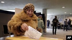 A Latvian woman casts her ballot paper at a polling station during a language referendum in Riga, Latvia, February 18, 2012.