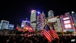 Pengunjuk rasa memegang bendera AS saat demonstrasi di Hong Kong, Kamis, 28 November 2019. Kemarahan China atas keputusan Presiden Donald Trump untuk menandatangani undang-undang yang mendukung hak asasi manusia di Hong Kong terlihat jelas. (Foto: AP)