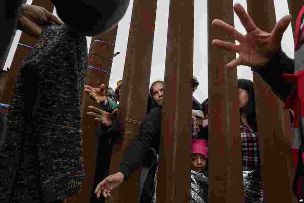 Migrantes reciben vestimentas para pasar los días en el muro fronterizo que entrew México y EEUU. Los voluntarios los asisten mientras esperan a ser aceptados en el lado estadounidense bajo asilo el viernes 12 de mayo de 2023 en San Diego. [Foto: Gregory Bull]