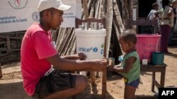 Un membre de l'ONG Action Contre la Faim donne de l'eau potable à un nourrisson lors d'une séance de dépistage de la malnutrition dans la commune d'Ifotaka, dans le sud de Madagascar, le 14 décembre 2018.