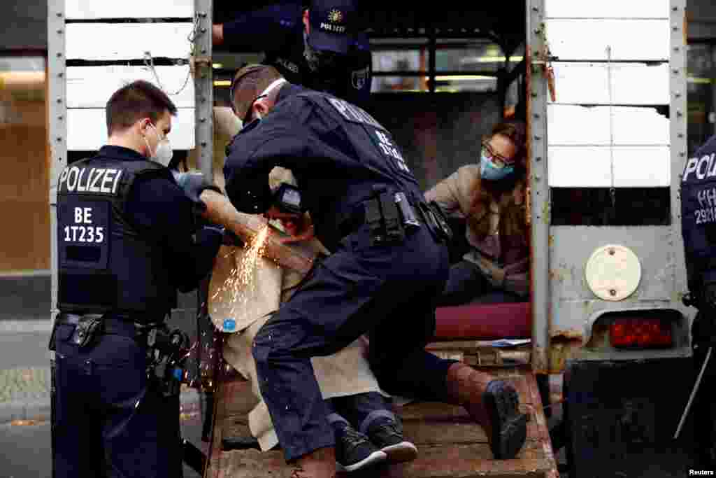 A police officer cuts a chain open to free a demonstrator as Extinction Rebellion activists protest in front of the Ministry of Agriculture in Berlin, Germany.