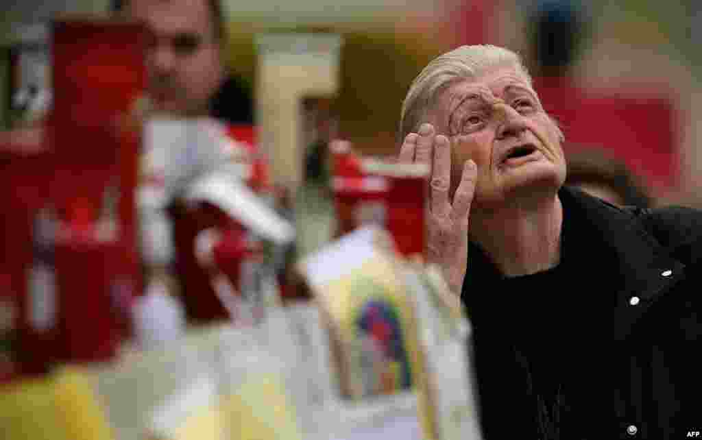 A woman prays outside the Gemelli hospital where Pope Francis is hospitalized with pneumonia, in Rome.