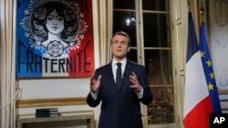 FILE - French President Emmanuel Macron gestures as he poses for a photograph after the recording of his New Year's speech at the Elysee Palace, in Paris, France, Dec. 31, 2018.